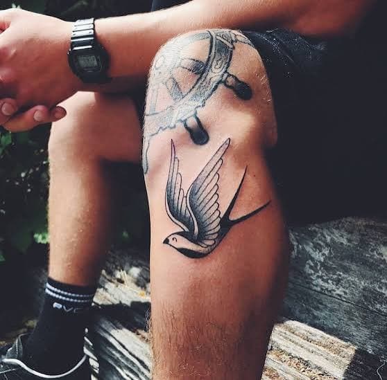 Traditional swallow tattoo on a seated person’s leg